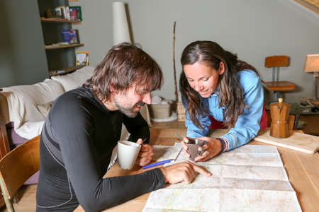 couple of mountaineers sitting having coffee planning the route looking at a map in a shelter - focus on a young womanの写真素材