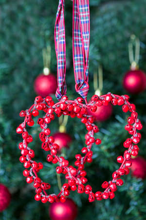 closeup of two red hearts hanging on a decorated Christmas tree background - focus on the heartsの写真素材