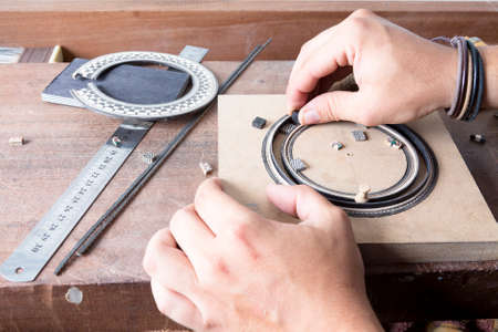 closeup of the hands of a luthier working a guitar rosette - focus on the rosette