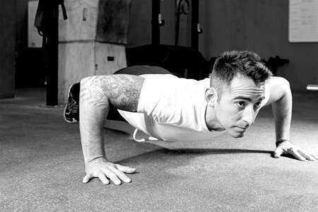 young male athlete is making push-ups at the crossfit box, lower position - focus on the man