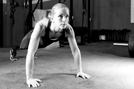 young female athlete is making push-ups at the crossfit box - focus on the woman