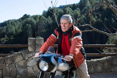portrait of a middle aged male mechanic sitting on his classic motorbike after its restoration - focus on the man faceの写真素材