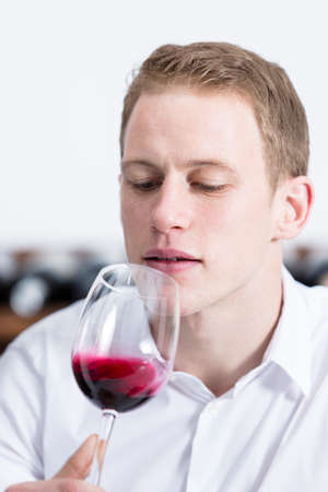 man on a wine tasting session on the olfactory phase is analyzing the red wine shaking the glass of...