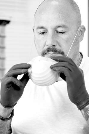 tattoo artist is putting on a mask in the tattoo cabin before a tattoo session at the tattoo shop -...