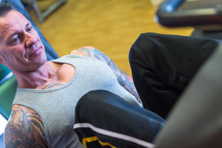 young man making leg press exercise at the gym - start exercise - focus on the man face