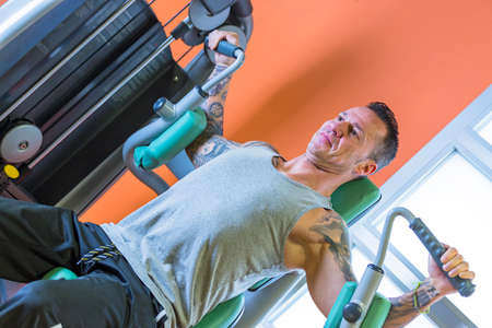 man making pec deck fly - chest exercise - at the gym - start exercise - focus on the man face