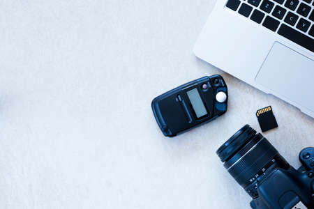 top view of a desktop of a photographer consisting on a camera, a laptop, a photometer and a memory card on a desk background - suitable for copy spaceの写真素材