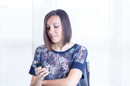 young woman looking at a reader after scanning the sensor of the glucose monitoring system at home -...