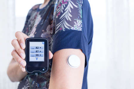 closeup of a hand of a young woman showing the reader after scanning the sensor of the glucose...