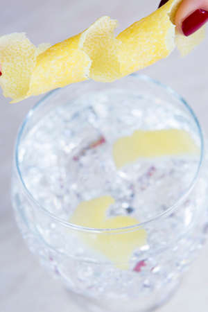 detail of a curled lemon peel like decoration element of a gin tonic balloon glass on a gin tonic preparation session - focus on the curled lemon peelの写真素材