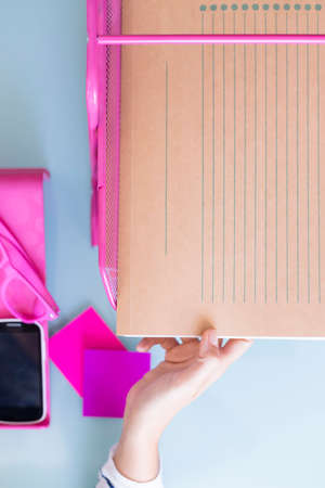 top view of a hand of a woman taking a folder from a letter tray on a working desk - focus on the...