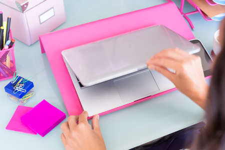 closeup of the hands of a woman opening a laptop on a working desk starting a working day - focus on...