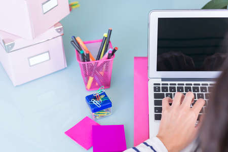 top view of a rear view of a woman working with a laptop on a working desk - focus on the ring fingerの写真素材
