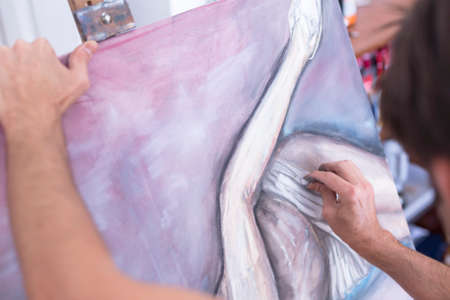 detail of the hand of a painter painting with chalk on canvas - focus on the white paintの写真素材