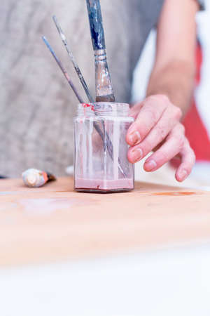 closeup of a hand of a painter cleaning the paintbrushes at his painting studio - focus on the paintbrushの写真素材