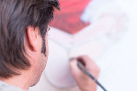 back view of a painter is painting on canvas at his painting studio - focus on the eyeの写真素材