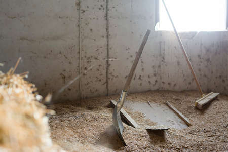 barn tools consist of a spade and a broom at the stable - useful as a background - focus on the spadeの写真素材