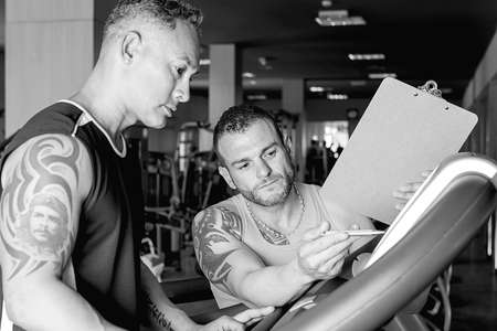 personal trainer explaining an exercise routine to man at the gym - focus on the trainer right eyeの写真素材