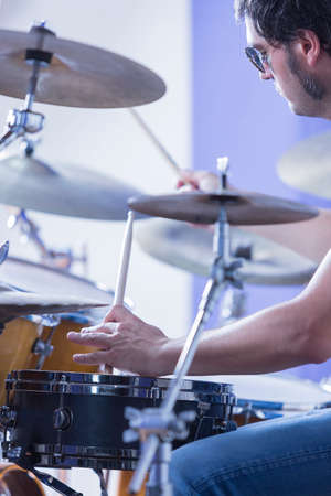 detail of the hand of a drummer that is holding drumsticks playing drums in a recording studio - focus on the left handの写真素材