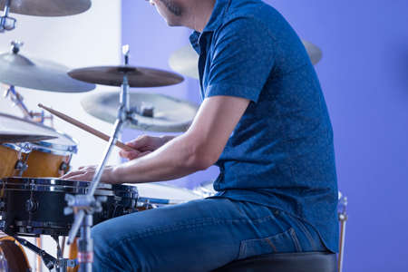detail of the hands of a drummer is playing drums in a recording studio - focus on the left handの写真素材