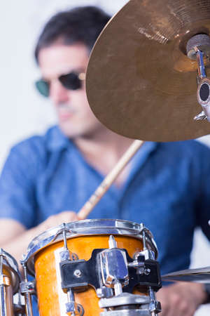 unfocused young male musician is playing set of drums in a recording studio - focus on the top of the drumの写真素材