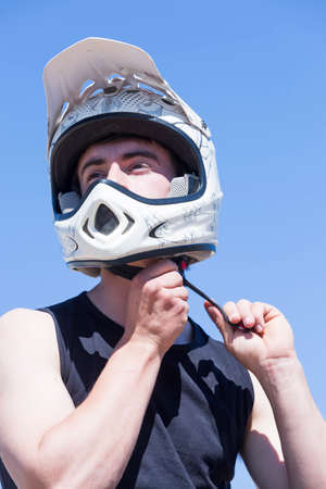 closeup of a young man BMX rider is adjusting the helmet on a BMX session in the mountain - focus on the left eyeの写真素材