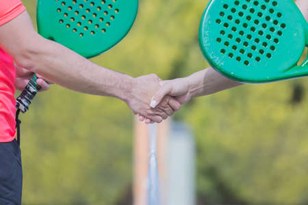 woman and man paddle players are giving a handshake at the starting a paddle match outdoors - focus on the thumbの写真素材