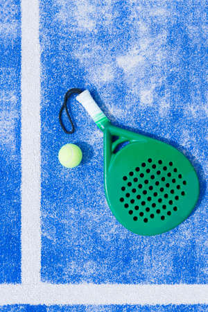 view from above of a green paddle racket and a ball in the line of a blue synthetic paddle tennis court useful as a background - focus on the center of the imageの写真素材