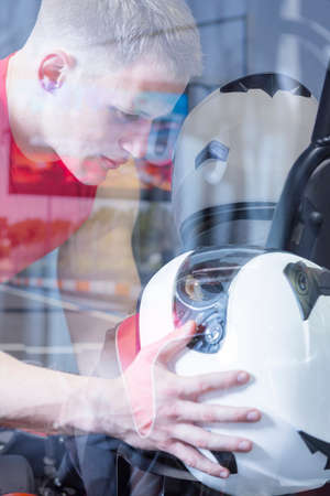 double exposure of a young man holding an helmet before starting a race in an outdoor go karting circuit - focus on the eyeの写真素材