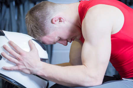 concentrated young man is resting his head on  an helmet before starting a race in an outdoor go karting circuit - focus on the eyeの写真素材