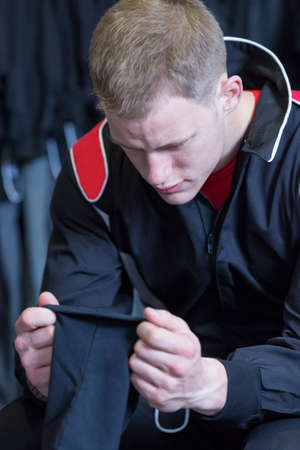 young man is putting on the sottocasco before starting a race in an outdoor go karting circuit - focus on the faceの写真素材