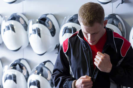 boy is putting on the driving suit before starting a race in an outdoor go karting circuit - focus on the faceの写真素材