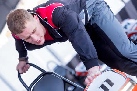 young man engineer is placing a gokart at the garage after a race in an outdoor go karting circuit - focus on the frownの写真素材