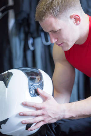 young man holding an helmet before starting a race in an outdoor go karting circuit - focus on the eyeの写真素材