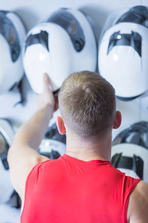 young man is choosing a helmet before starting a race in an outdoor go karting circuit - focus on the headの写真素材
