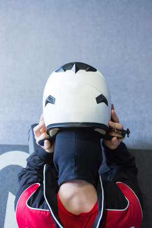 view from above of a young man putting the helmet on before starting a race in an outdoor go karting circuit - focus on the helmetの写真素材