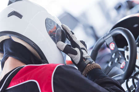 back view of a concentrated karting pilot sitting on his go-kart before starting a race in an outdoor go karting circuit - focus on the thumbの写真素材