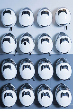 set of karting helmets hung on the wall useful as a sport background - focus on the center of the imageの写真素材