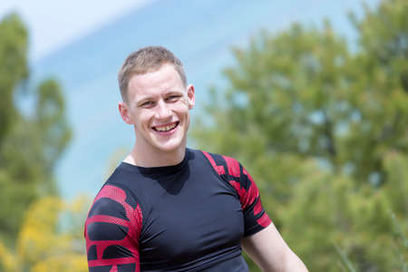 closeup of a smiling young male runner before starting a running session outdoors - focus on the...