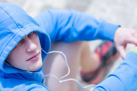 view from above of a young male runner is resting listening music after a running session outdoor looking at the camera - focus on the left eyeの写真素材