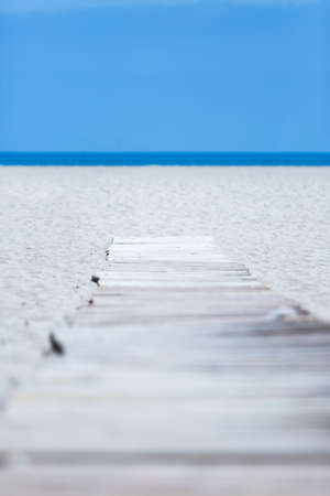 wooden path over sand of the beach to the sea useful as a background - focus at the end of the footbridgeの写真素材