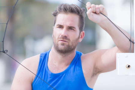 closeup of a portrait of a young male volley player on the volleyball net on a sand court at the...