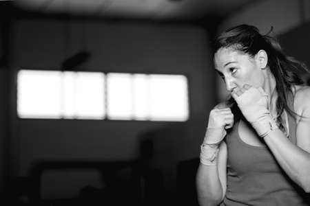 Professional female athlete boxing in gym. Black and whiteの写真素材