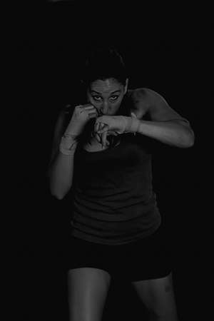 Portrait of strong female boxer preparing to fight while looking at camera.Black and white. Isolated