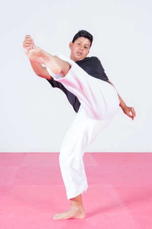 Young teenager dancing capoeira in gym-hall on white backgroundの写真素材