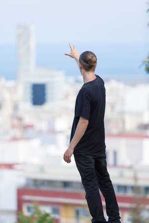 Back view of young hipster pulling his hand away. Waterscapeの写真素材