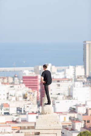 Back view of young man looking away while standing on roofの写真素材