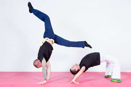 Two acrobats dancing capoeira against of white backgroundの写真素材