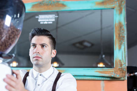 Portrait of serious bartender working, grinding coffee beansの写真素材