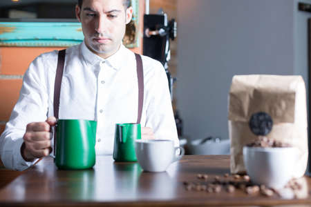 Barista and two pitchers on tableの写真素材